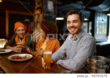 Happy smiling man sitting at sports bar counter desk looking at camera 99765679