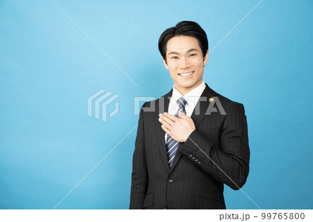 ブルーバックで胸に手をあてて微笑む弁護士 99765800