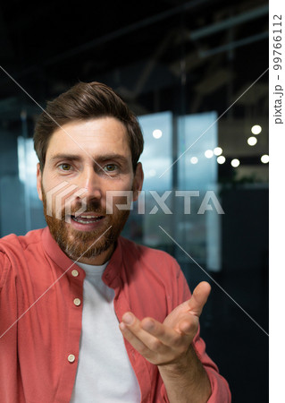 Close-up photo. Young businessman, freelancer, programmer conducts a video conference on a video call, holds a phone in his hands, talks to the camera, vertical photo. Close-up photo. Young businessman, freelancer, programmer conducts a video conference on a video call, holds a phone in his hands, talks to the camera, vertical photo. 99766112