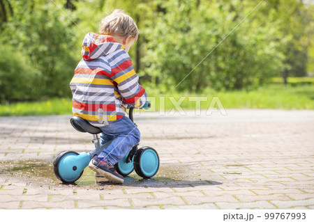 Active blond boy riding balance bike or run bike outdoor park Active blond boy riding balance bike or run bike outdoor park 99767993