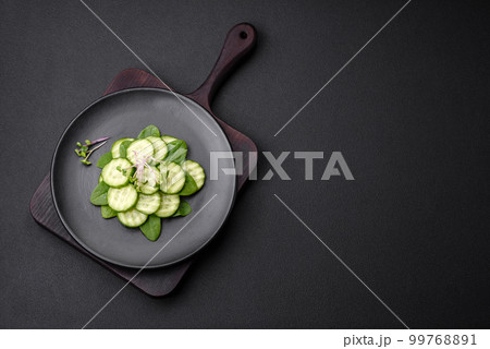 Delicious healthy raw cucumber sliced on a black ceramic plate 99768891