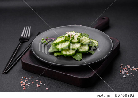 Delicious healthy raw cucumber sliced on a black ceramic plate 99768892