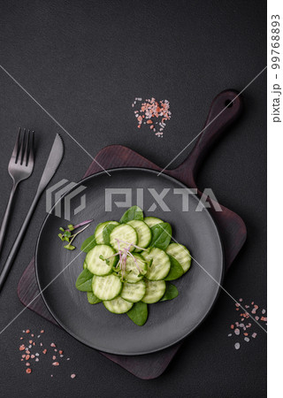 Delicious healthy raw cucumber sliced on a black ceramic plate 99768893