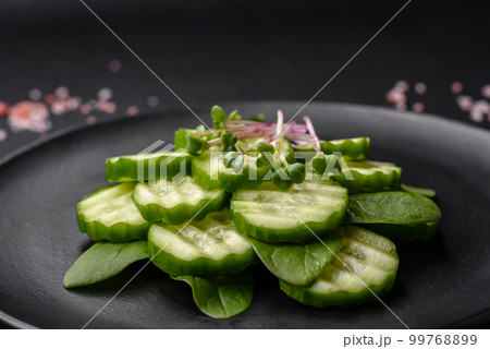 Delicious healthy raw cucumber sliced on a black ceramic plate 99768899