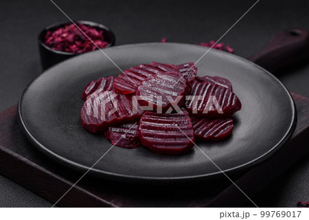 Delicious healthy boiled ruby-colored beets sliced on a black plate 99769017