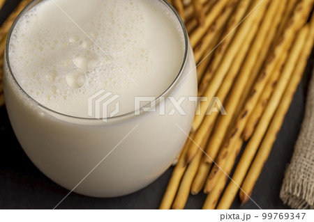 Thin and long bread sticks made of wheat flour and a glass of milk Thin and long bread sticks made of wheat flour and a glass of milk 99769347