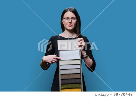 Young woman choosing decorative fabrics for interior, on blue background 99770448
