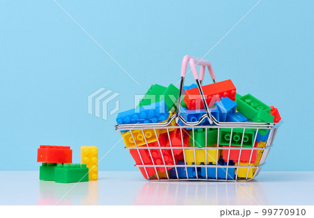 Plastic colorful building blocks in a miniature metal shopping cart, educational game for children Plastic colorful building blocks in a miniature metal shopping cart, educational game for children 99770910
