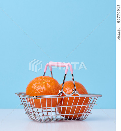 Ripe mandarins in a miniature metal shopping cart on a blue background, citrus price increase concept Ripe mandarins in a miniature metal shopping cart on a blue background, citrus price increase concept 99770912