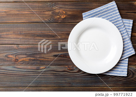 Top view on colored background empty round white plate on tablecloth for food. Empty dish on napkin with space for your design Top view on colored background empty round white plate on tablecloth for food. Empty dish on napkin with space for your design 99771922
