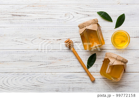 Honey jar with wooden honey dipper on white background top view with copy space. Delicious honey bottle Honey jar with wooden honey dipper on white background top view with copy space. Delicious honey bottle 99772158