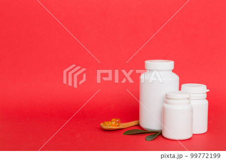 Omega-3 capsules lie in white bottle on a table with green leaves background. Fish oil tablets. Biologically active additives. omega 6, omega 9, vitamin A, E, D, vitamin D3 top view with copy space 99772199