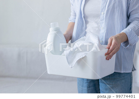 Woman holds basket with dirty laundry bottle of detergent in her hands. Cleaning wash cleanliness 99774401