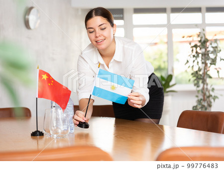 Young female attendant putting up flags for international negotiations between china and argentina 99776483