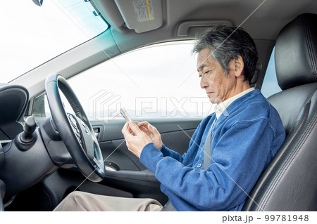 自動車を停めてスマートフォンを使うシニア男性 99781948