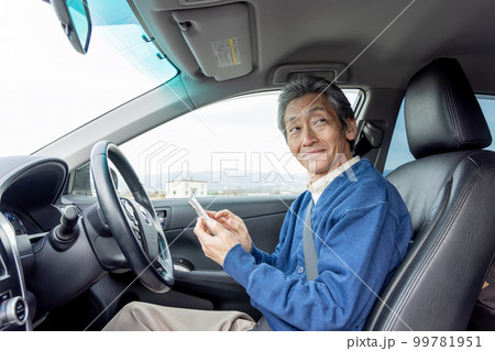 自動車を停めてスマートフォンを使うシニア男性 99781951