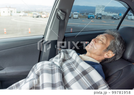 自動車の運転に疲れ仮眠をとるシニア男性 99781958