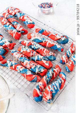 Drizzling white glaze on top of patriotic cinnamon twists. and decorating with star sprinkles. Drizzling white glaze on top of patriotic cinnamon twists. and decorating with star sprinkles. 99784218