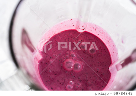 Mixing ingredients in kitchen blender to prepare mixed berry boba smoothie. 99784345