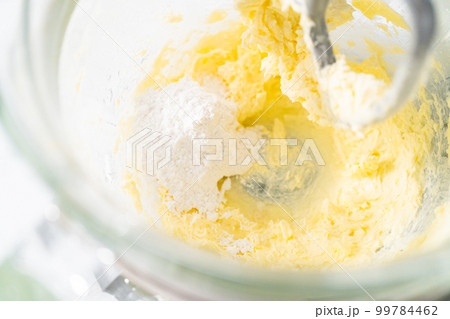 Mixing ingredients in kitchen electric mixer to make lemon buttercream frosting. 99784462