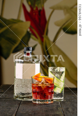 Side view on gin cocktails in glasses with bottle 99784631