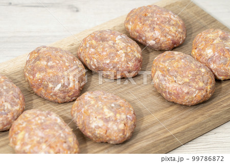 raw homemade meatballs on a massive board made of natural wood raw homemade meatballs on a massive board made of natural wood 99786872
