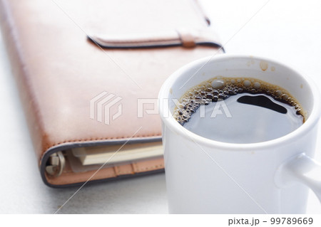 茶色の革のシステム手帳とブラックコーヒー 茶色の革のシステム手帳とブラックコーヒー 99789669