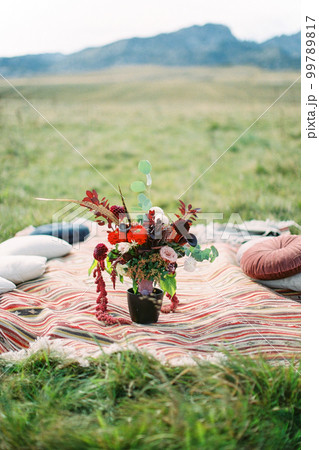 Wedding bouquet stands in a vase on a homespun bedspread on a green lawn 99789817