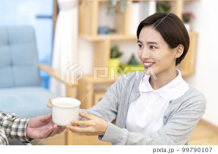 お茶を渡す介護士 99790107