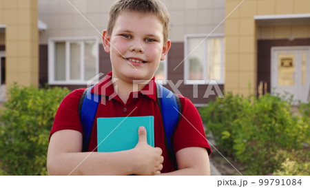 boy student with book his hand smiling. happy family. child with school backpack textbook his hands looks into frame. face child schoolboy. happy child kid teenager schoolboy school yard. education boy student with book his hand smiling. happy family. child with school backpack textbook his hands looks into frame. face child schoolboy. happy child kid teenager schoolboy school yard. education 99791084