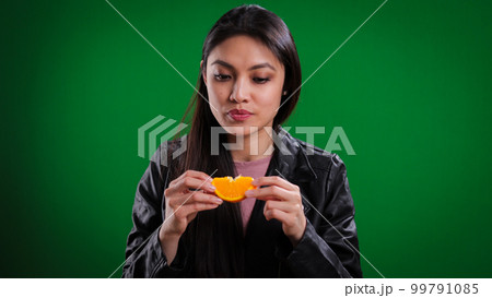 Young woman bites into an orange slice Young woman bites into an orange slice 99791085