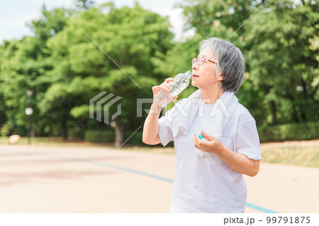 公園で水を飲みながら運動・ウォーキング・歩く高齢者女性 99791875