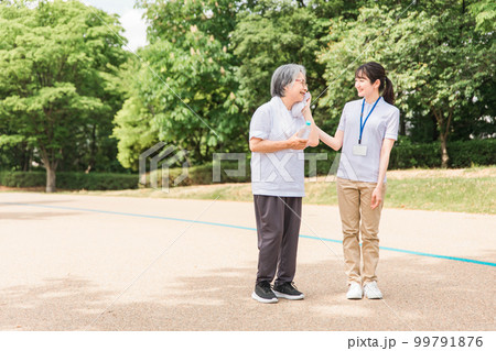 公園で運動・ウォーキング・歩く高齢者と介護士・看護師・理学療法士・運動指導員の女性 99791876