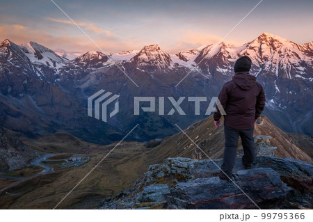 Hiker above Hohe Tauern mountain range dramatic Grossglockner road, Austria Hiker above Hohe Tauern mountain range dramatic Grossglockner road, Austria 99795366