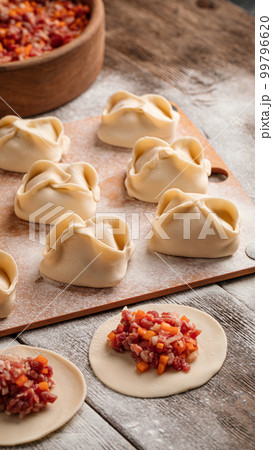 Semi finished manti dumplings on board with flour Semi finished manti dumplings on board with flour 99796620