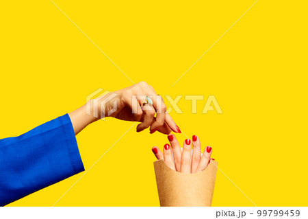 Female fingers instead of fries into packaging against yellow studio background. Surrealism and creativity. Food pop art photography. Fast food 99799459