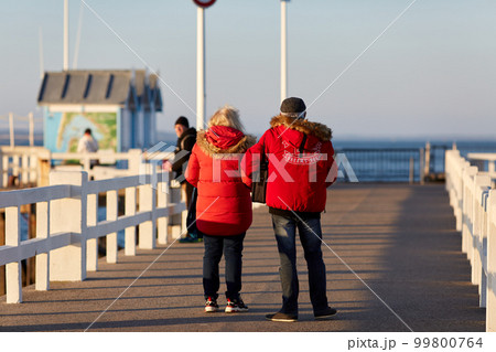 couple walking on the pieron a sunny day 99800764
