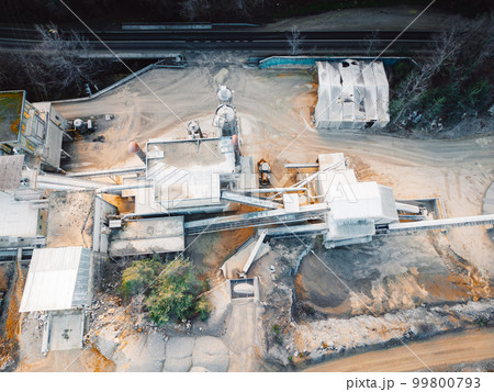 Dusty grounds at the small working quarry, heavy machinery and trucks on the grounds  99800793