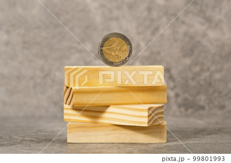 Two Euros coin balancing on a wooden blocks tower Two Euros coin balancing on a wooden blocks tower 99801993