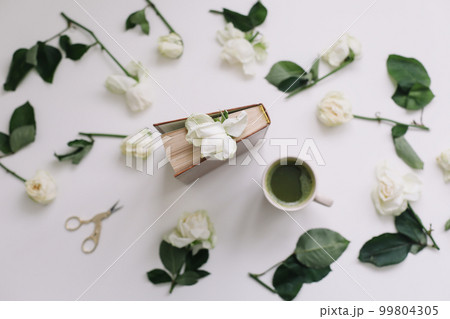 Floral pattern of white flowers and petals, green leaves on a white background. Beautiful elegant luxurious composition with white roses. Top view. Minimal art. Florist, flowers delivery concept 99804305