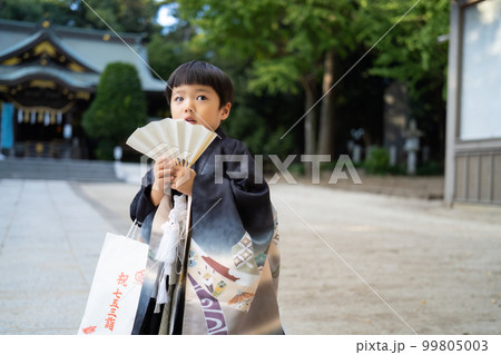 和服姿で七五三のお宮参りに来た5歳児が神社の境内でちょっと心配そうに話している図 99805003