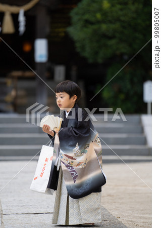 和服姿で七五三のお宮参りに来た5歳児が神社の境内を歩いているところ 99805007