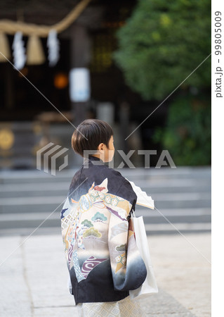 和服姿で七五三のお宮参りに来た5歳児が神社の境内を歩いている後ろ姿 99805009