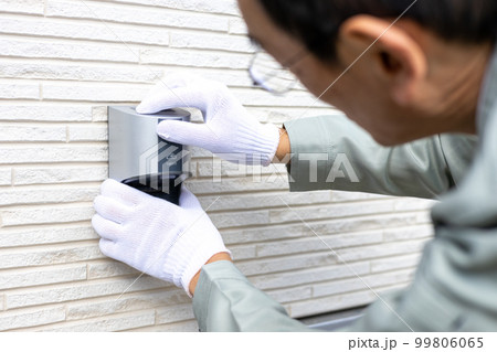 一戸建住宅の屋外コンセントの工事をしている男性作業員 99806065