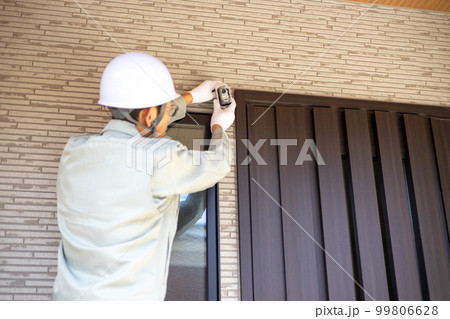 一戸建て住宅の玄関に防犯カメラを取り付けようとしているところ 99806628