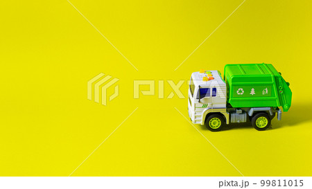 The toy is a garbage truck green with a white body on a yellow background banner with a place for text for a toy store. Children's toys typewriter. 99811015