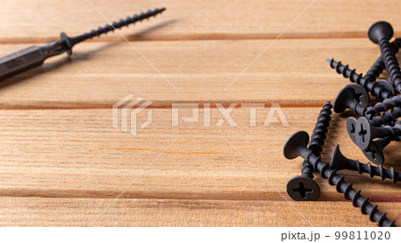 A screwdriver and self-cutters on a brown wooden background. Building tools to repair the house. A screwdriver and self-cutters on a brown wooden background. Building tools to repair the house. 99811020
