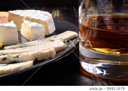 Whiskey in a glass and an appetizer for whiskey blue cheese and Camembert cheese. Appetizer for alcohol, dear spirits. 99811078