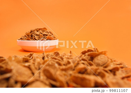 Close-up of wheat flakes on orange background, quick cereal healthy breakfasts. Close-up of wheat flakes on orange background, quick cereal healthy breakfasts. 99811107