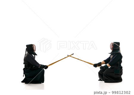 Start of fight. Two men, professional kendo athletes in uniform with helmet with bamboo shinai sword against white studio background 99812302